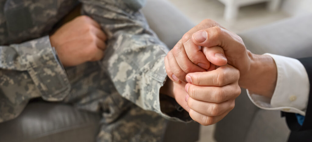 Veteran holding a supportive hand. By understanding how mental health issues contribute to veteran homelessness, we can better address the needs of those who have served our country.