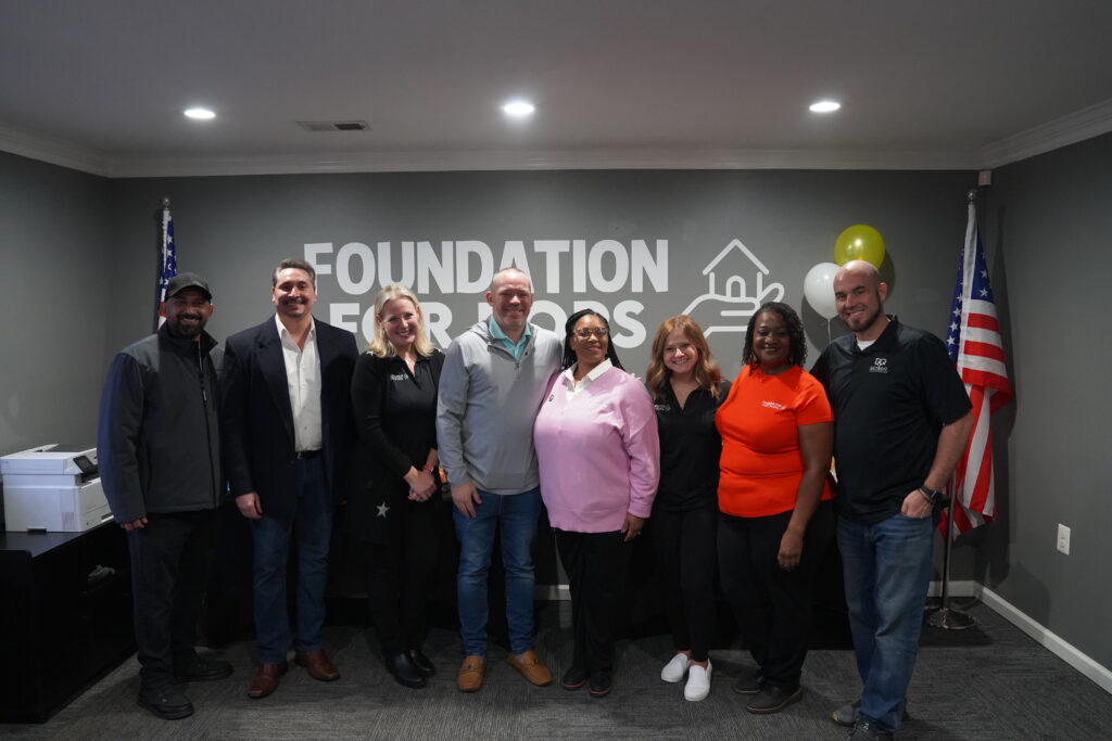 The Foundation For Pops board posing in front of the logo at our new offices in Melvindale, MI.